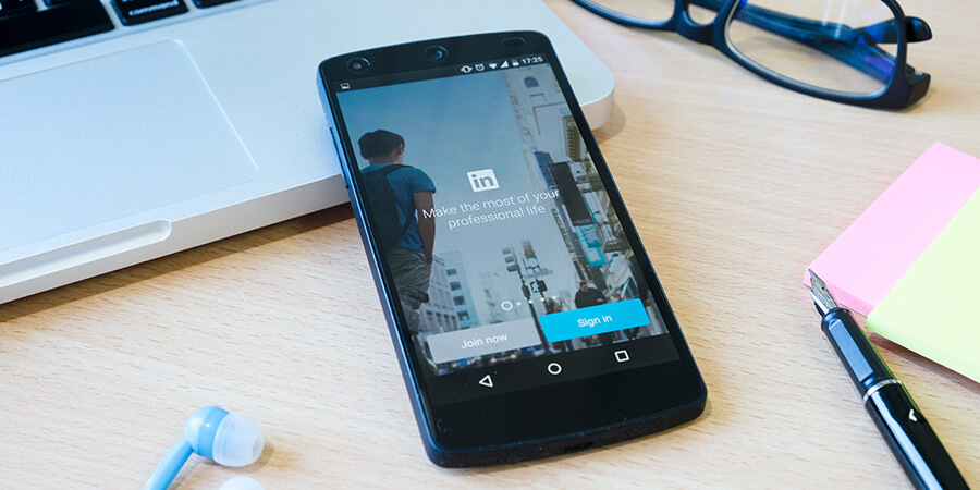 Laptop, phone and glasses. Linkedin login on phone.