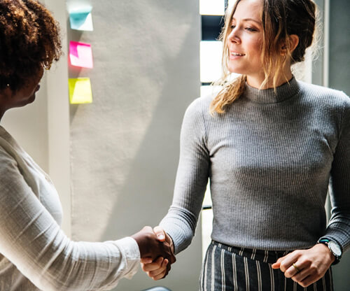 Be aware of your facial expressions Two young professional women shaking hands.