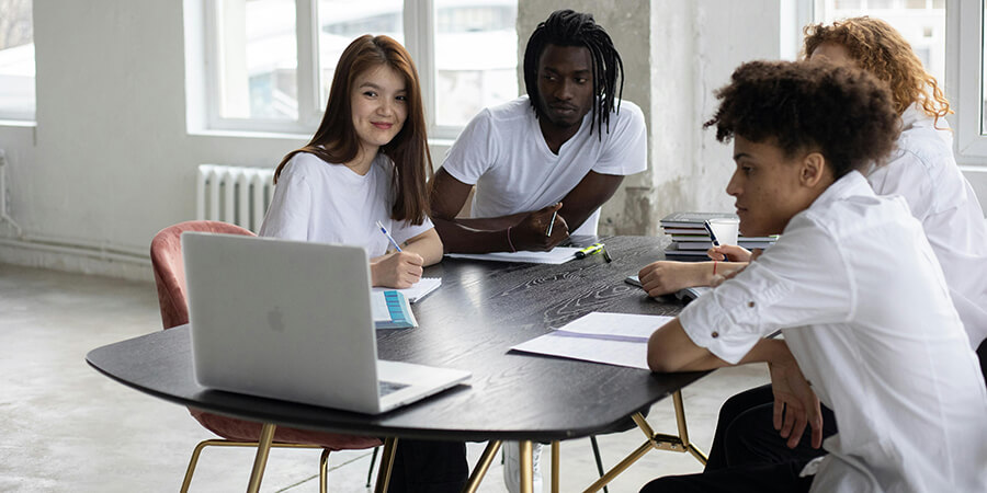 Graoup of people sitting around an oval desk having a remote meeting.