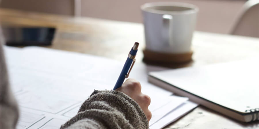 Person taking notes with a pen and paper.